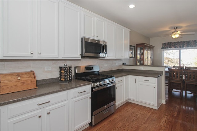 kitchen featuring tasteful backsplash, appliances with stainless steel finishes, kitchen peninsula, white cabinets, and dark hardwood / wood-style floors