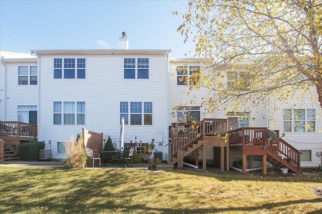 back of property with a wooden deck and a lawn