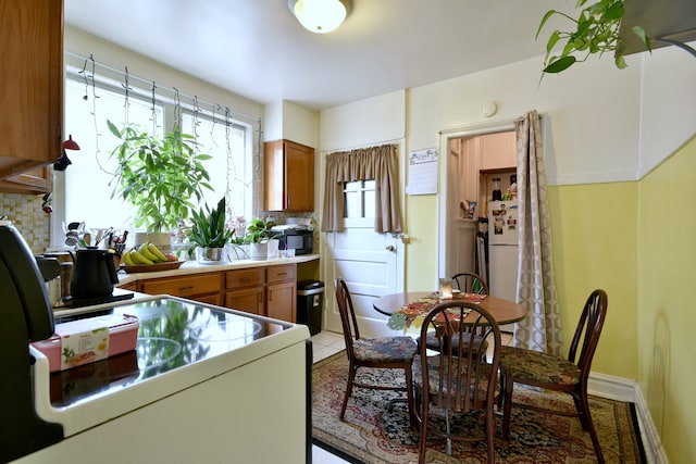 kitchen featuring range, light tile patterned flooring, white fridge, and tasteful backsplash