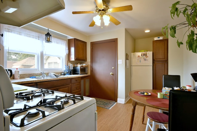 kitchen featuring light hardwood / wood-style flooring, backsplash, sink, white appliances, and ceiling fan