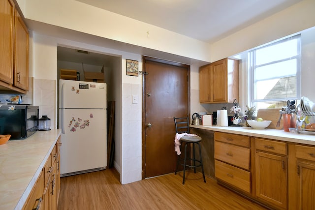 kitchen with light hardwood / wood-style flooring and white fridge