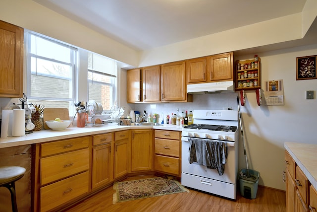 kitchen with light hardwood / wood-style flooring, white gas range oven, and tasteful backsplash