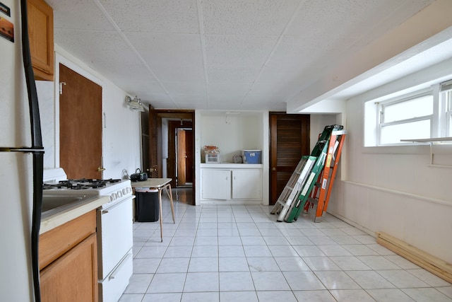 kitchen featuring light tile patterned floors, white gas range oven, stainless steel refrigerator, and a baseboard radiator