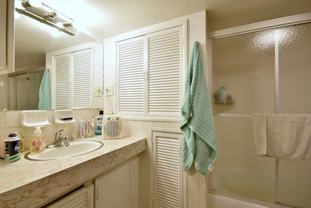 bathroom with a shower with door, vanity, and backsplash