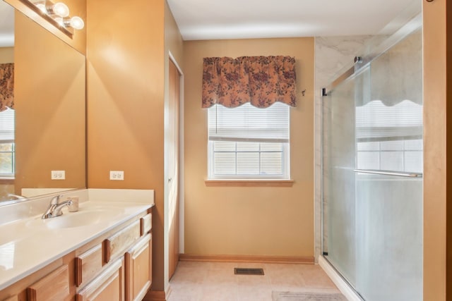 bathroom featuring a shower with door, vanity, and plenty of natural light