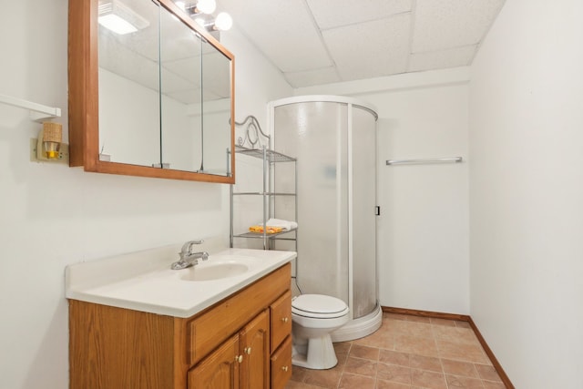 bathroom with a shower with shower door, toilet, a paneled ceiling, vanity, and tile patterned flooring