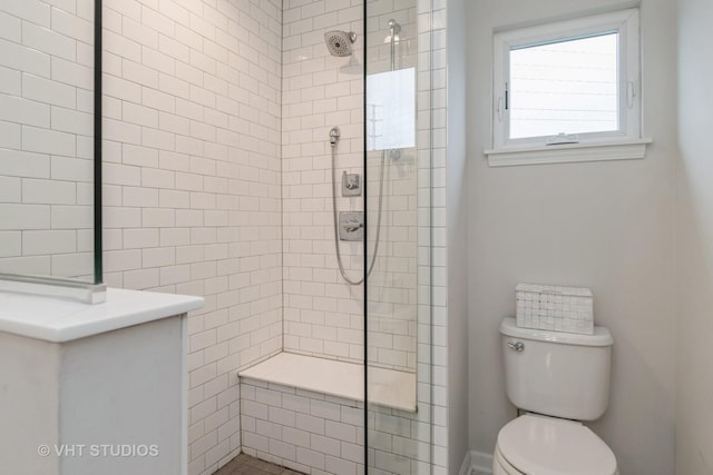 bathroom with a tile shower and toilet