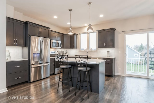 kitchen featuring dark wood-type flooring, a kitchen island, pendant lighting, and appliances with stainless steel finishes