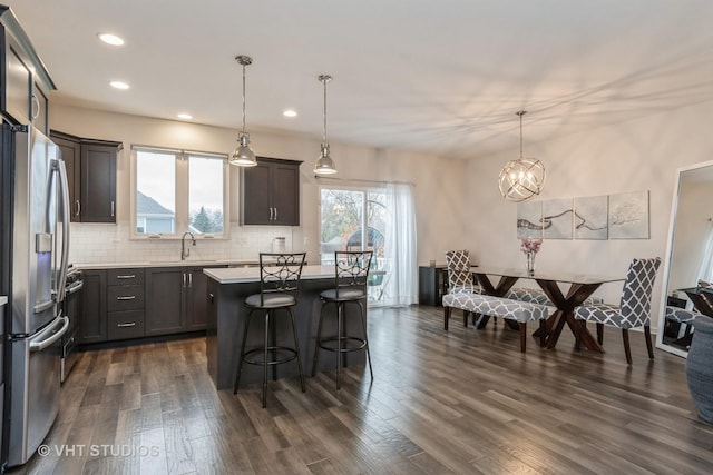 kitchen with pendant lighting, stainless steel fridge, a kitchen island, and dark wood-type flooring