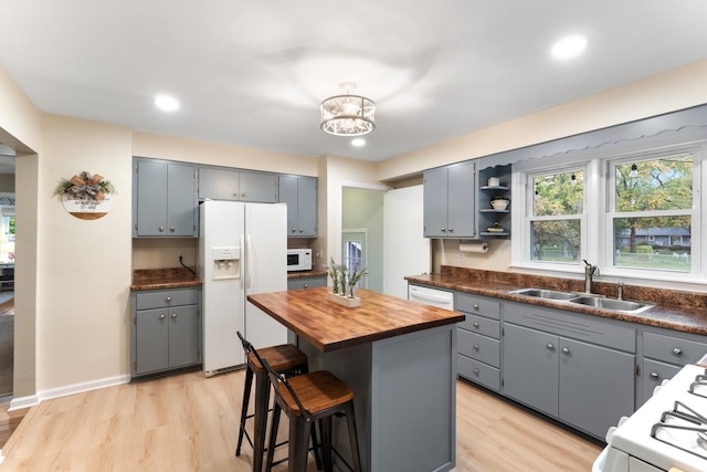 kitchen with a kitchen island, light wood-type flooring, gray cabinetry, sink, and white appliances