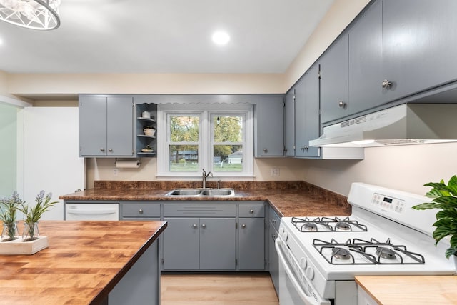 kitchen featuring butcher block countertops, sink, light wood-type flooring, and white appliances