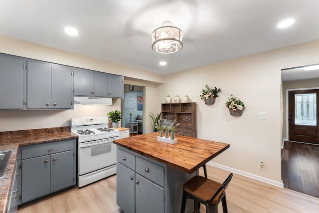 kitchen with light hardwood / wood-style floors, white gas stove, a center island, and gray cabinets