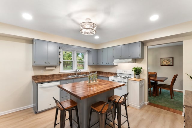 kitchen featuring white appliances, sink, light hardwood / wood-style floors, wooden counters, and an inviting chandelier