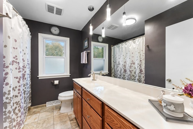 bathroom with a wealth of natural light, vanity, toilet, and tile patterned flooring