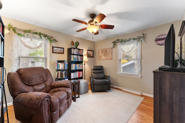 sitting room with a baseboard heating unit, light wood-type flooring, and ceiling fan