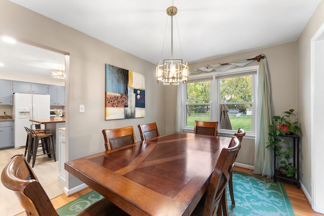 dining area with light hardwood / wood-style floors and a notable chandelier