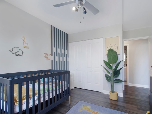 bedroom featuring a closet, a nursery area, dark wood-type flooring, and ceiling fan