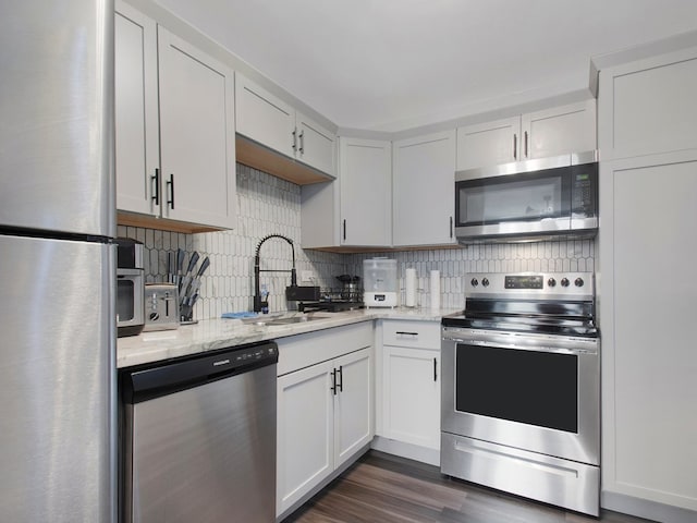 kitchen with appliances with stainless steel finishes, white cabinets, sink, and dark hardwood / wood-style flooring