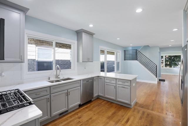 kitchen with sink, light hardwood / wood-style flooring, appliances with stainless steel finishes, and a wealth of natural light