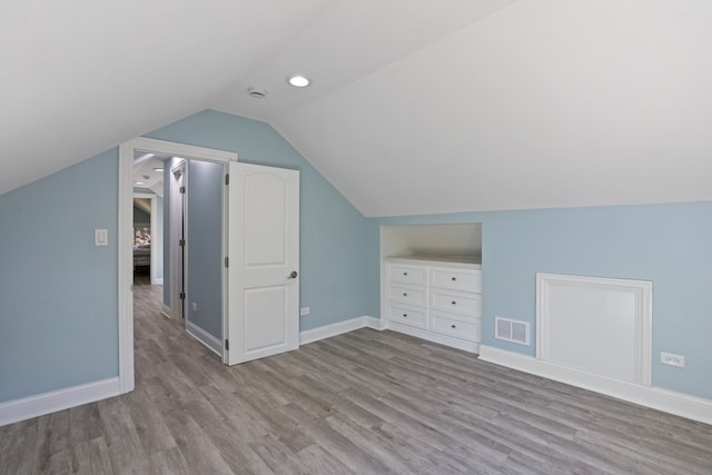 additional living space featuring light hardwood / wood-style floors and lofted ceiling