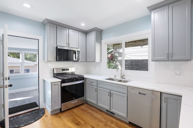 kitchen with stainless steel appliances, sink, light wood-type flooring, and a wealth of natural light