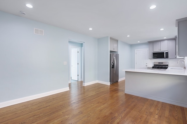 kitchen with gray cabinetry, appliances with stainless steel finishes, and dark hardwood / wood-style flooring