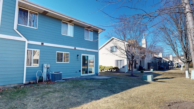 rear view of property with cooling unit and a lawn