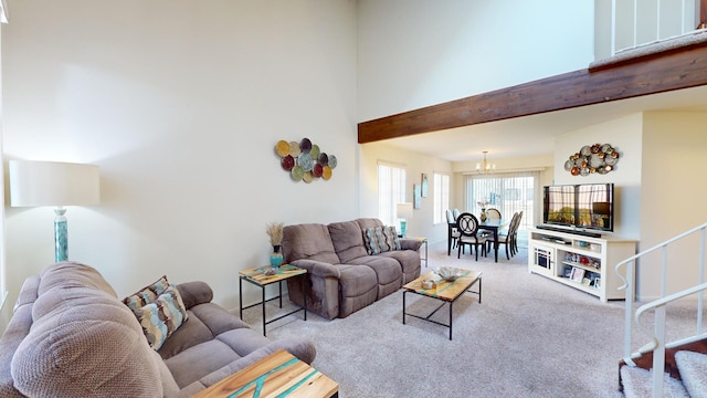 carpeted living room featuring a towering ceiling and a chandelier