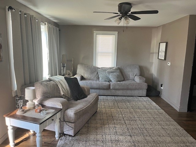 living room featuring ceiling fan and dark hardwood / wood-style flooring