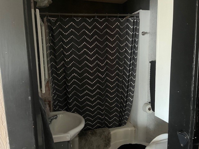 full bathroom with sink, shower / bath combo with shower curtain, and toilet