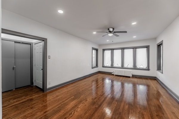 interior space with radiator heating unit, ceiling fan, and dark hardwood / wood-style floors