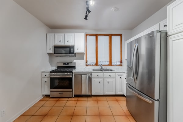 kitchen with white cabinetry, light tile patterned floors, stainless steel appliances, and sink