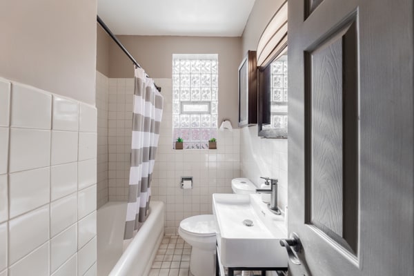 full bathroom with tile patterned floors, toilet, sink, shower / tub combo with curtain, and tile walls