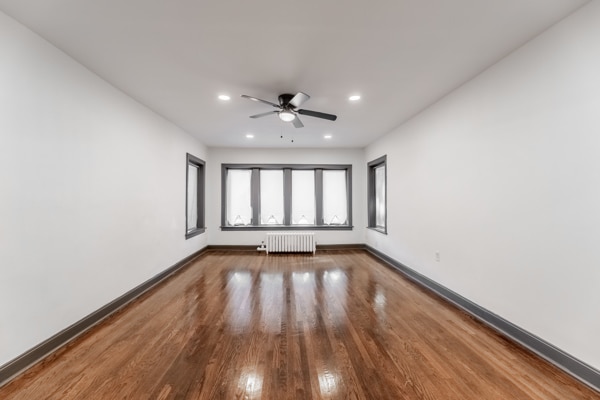 spare room featuring radiator, ceiling fan, and wood-type flooring