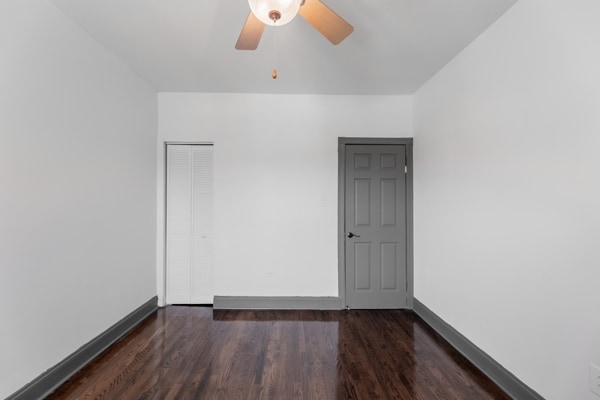 unfurnished room featuring dark wood-type flooring and ceiling fan