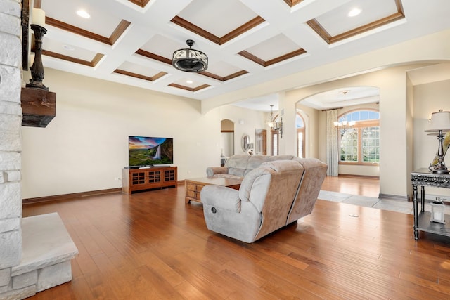 living room featuring a notable chandelier, coffered ceiling, beamed ceiling, and wood-type flooring