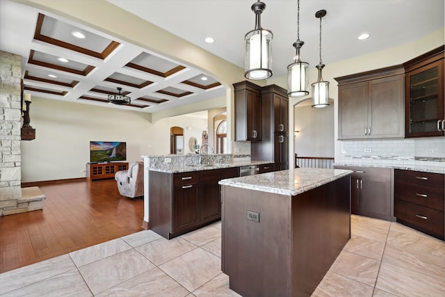 kitchen with decorative light fixtures, dark brown cabinets, light wood-type flooring, and a kitchen island