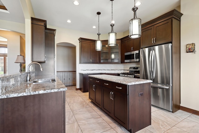 kitchen featuring dark brown cabinets, a kitchen island, appliances with stainless steel finishes, pendant lighting, and sink