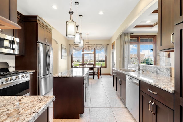 kitchen with appliances with stainless steel finishes, decorative backsplash, a kitchen island, and a wealth of natural light