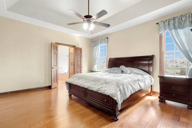 bedroom featuring ceiling fan, a raised ceiling, and light hardwood / wood-style flooring