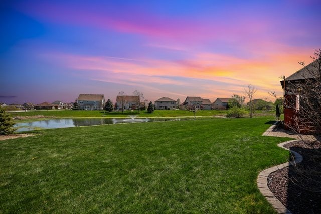 yard at dusk featuring a water view