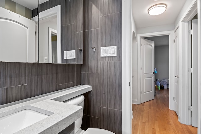 bathroom featuring vanity, toilet, hardwood / wood-style flooring, and tile walls