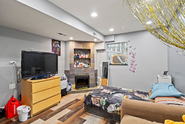 bedroom with a tiled fireplace and light wood-type flooring