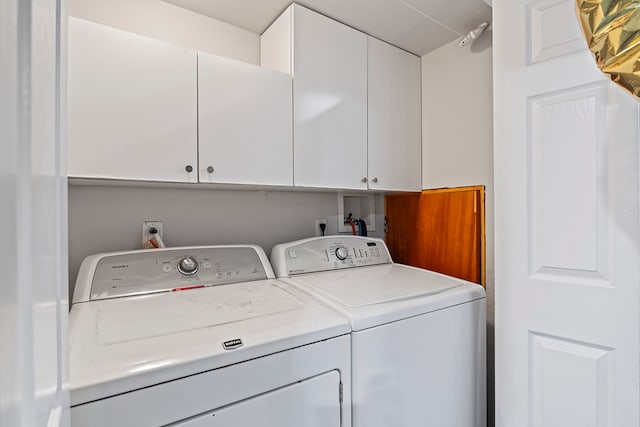 laundry room featuring washer and clothes dryer and cabinets