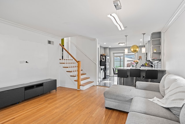 living room featuring ornamental molding and light wood-type flooring