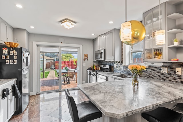 kitchen featuring backsplash, appliances with stainless steel finishes, a breakfast bar area, pendant lighting, and light stone counters