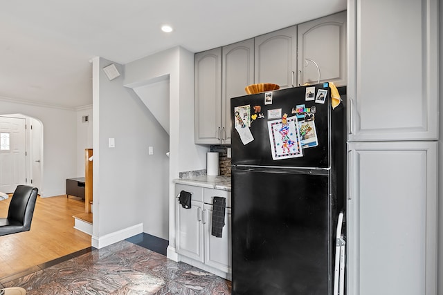 kitchen featuring crown molding, gray cabinets, dark hardwood / wood-style floors, and black refrigerator