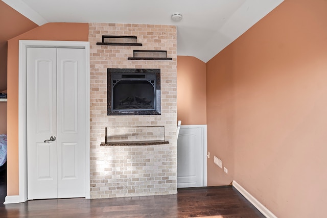 unfurnished living room featuring vaulted ceiling, a fireplace, and dark hardwood / wood-style floors