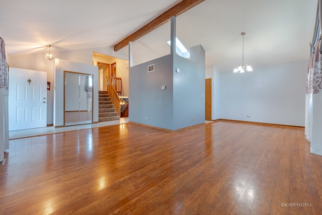 unfurnished living room featuring beam ceiling, high vaulted ceiling, wood-type flooring, and an inviting chandelier