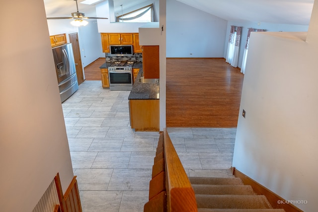 kitchen with decorative backsplash, stainless steel appliances, light wood-type flooring, high vaulted ceiling, and ceiling fan